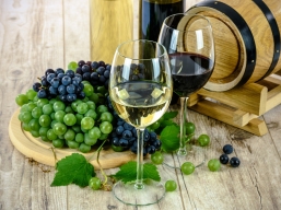 Weingläser und Weintrauben vor einem Holzfass auf Holzboden